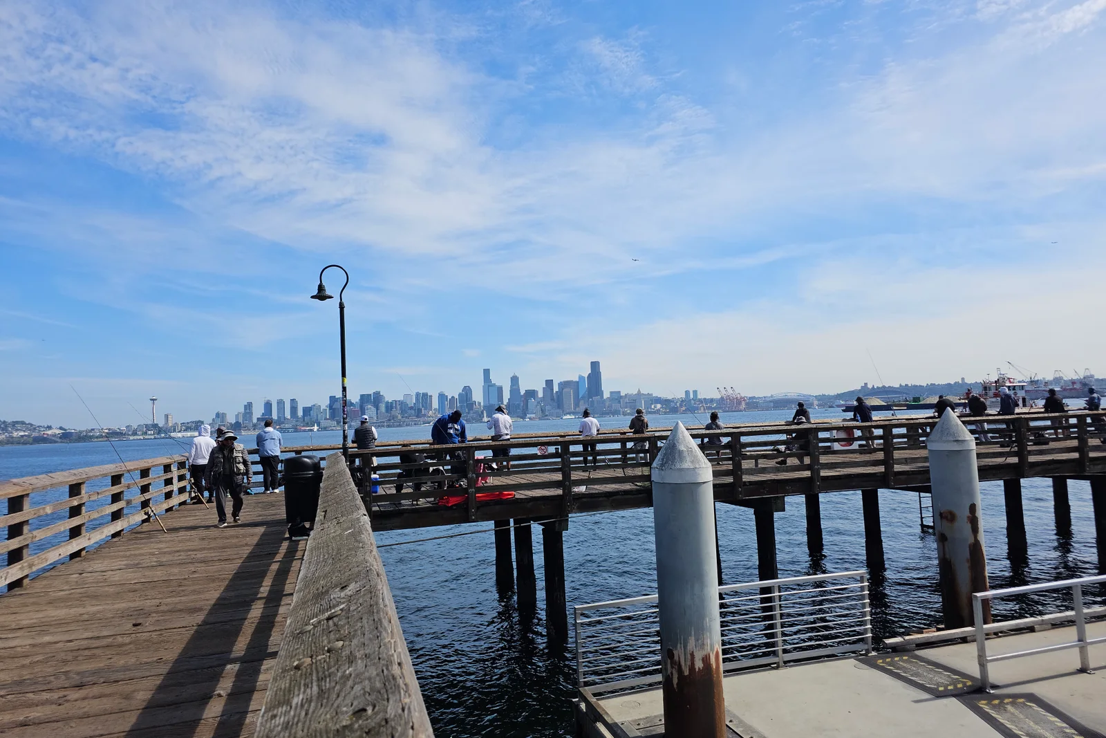 Anglers fishing from a Puget Sound pier with the Seattle skyline behind them
